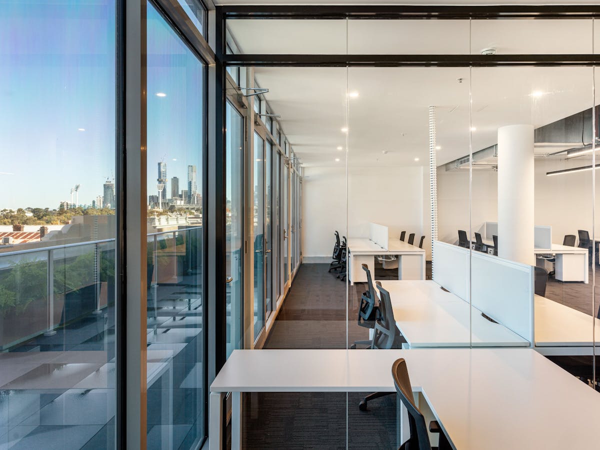 Open plan office along a glazed facade with the Melbourne skyline beyond